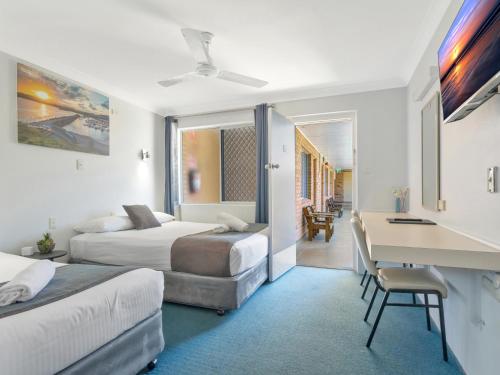 a hotel room with two beds and a desk at Bentleigh Motor Inn - Coffs Harbour in Coffs Harbour