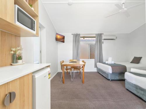 a hotel room with a bed and a table and a kitchen at Bentleigh Motor Inn - Coffs Harbour in Coffs Harbour