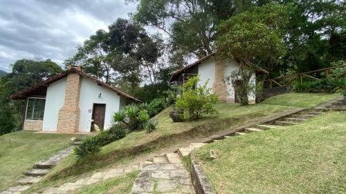 a small house on a hill next to a field at Chalé com vista deslumbrante in Teresópolis