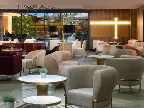 eine Lobby mit Sofas, Tischen und Stühlen in der Unterkunft The Emporium Hotel Plovdiv - MGallery Collection in Plowdiw