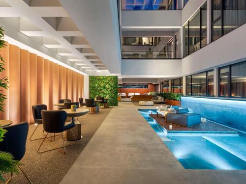 eine Hotellobby mit einem Pool, Tischen und Stühlen in der Unterkunft The Emporium Hotel Plovdiv - MGallery Collection in Plowdiw