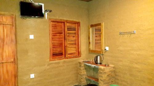baño con lavabo y TV en la pared en Golden Nature Cottage, en Udawalawe