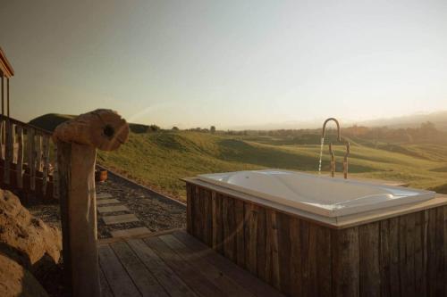Una bañera con grifo sobre una plataforma de madera. en Sunsets, outdoor bath, mountain views, fire pit, en Marotiri