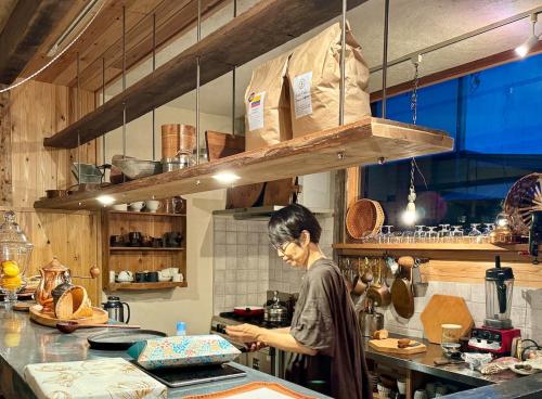 a woman standing in a kitchen preparing food at Private Forest Cottage for Two, Organic Lifestyle in Bungoono