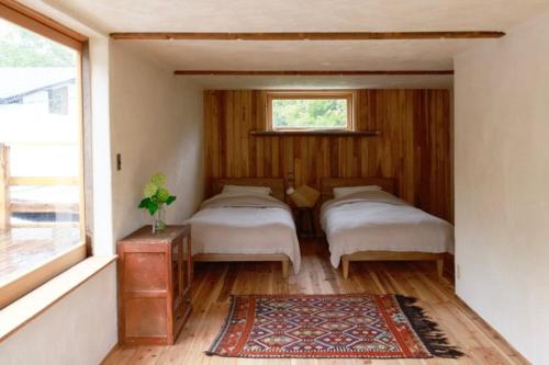 a bedroom with two beds and a window at Private Forest Cottage for Two, Organic Lifestyle in Bungoono