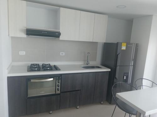 La mejor ubicación y tú mejor opción en Paipa في بايبا: مطبخ مع موقد وثلاجة