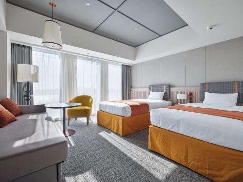 ein Hotelzimmer mit zwei Betten und einer Couch in der Unterkunft Premium hotel MONday MAIHAMA View 1 in Tokio