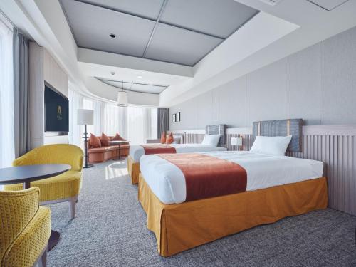 a hotel room with two beds and a table and chairs at Premium hotel MONday MAIHAMA View 1 in Tokyo