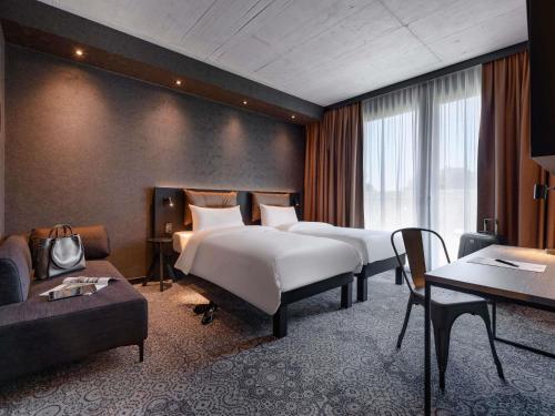 腓特烈港ibis Styles Friedrichshafen的一间酒店房间，配有两张床和一张沙发