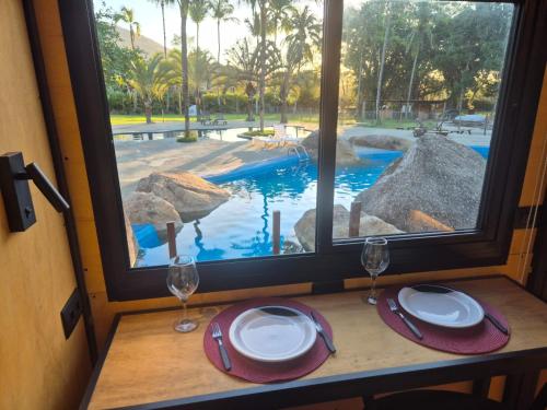 Una mesa con vasos y platos y una vista a una piscina. en Camping & Cabanas Ilhabela, en Ilhabela
