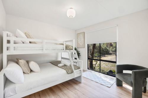 a white bedroom with a white bunk bed and a chair at Glenkeen Farm and Cabins in Bellbrae