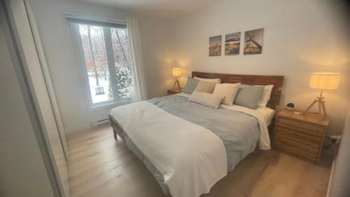 una camera da letto con un letto con lenzuola bianche e una finestra di Maison de vacances à l'Ile d'Orleans a St-Pierre-de-l'Île-d'Orléans