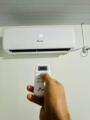 una persona que tenga un mando a distancia frente a un acondicionador de aire en La casita, en Foz do Iguaçu