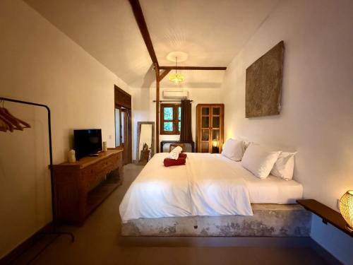 a bedroom with a white bed and a television at Joglo Villas Uluwatu - Tropical Oasis in Uluwatu