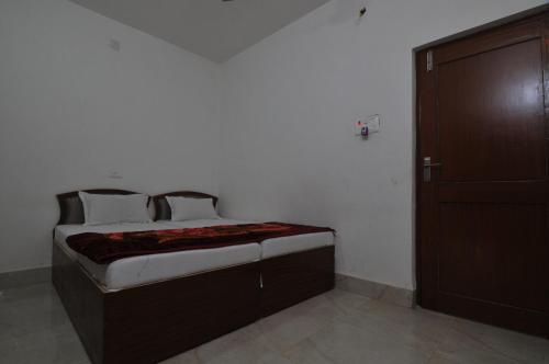 a bed in a room with a wooden door at Rama Guest House in Bodh Gaya