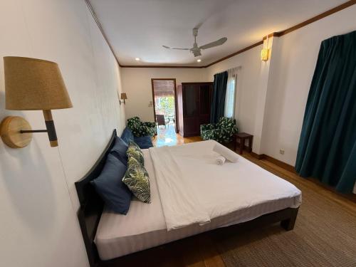 una camera da letto con un letto bianco con cuscini blu di Banksy's Siem Reap a Phumĭ Réach Born