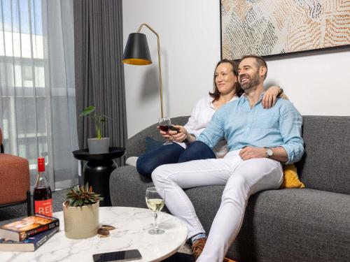 a man and a woman sitting on a couch at The Sebel Canberra Campbell in Canberra