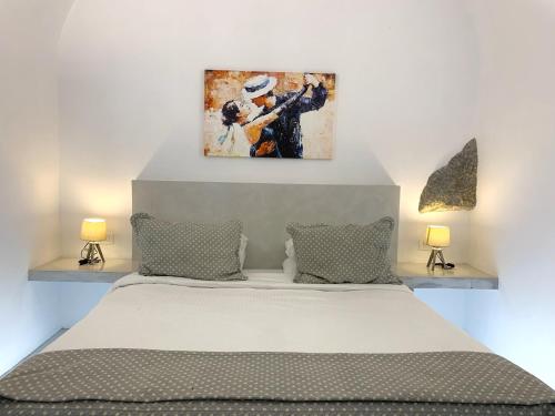 a bedroom with a bed with a painting above it at Lupi's Cave House in Fira