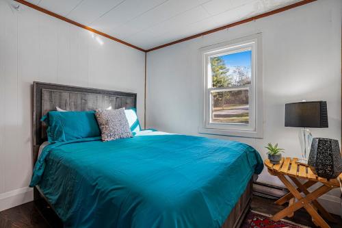 een slaapkamer met een blauw bed en een raam bij Rustic Lakefront Cottage with Fire Pit and Scenic Views in Brechin