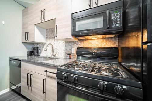 a kitchen with a stove and a microwave at Little Italy Gem Close to CWRU, Cleveland Clinic & Top Restaurants w King Bed in Cleveland