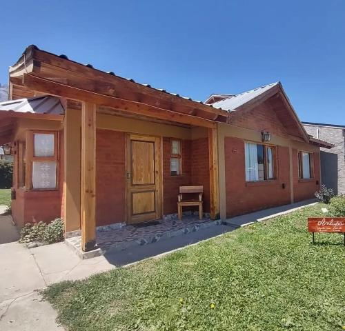 a small house with a wooden door in a yard at Anlupa Casa in El Bolsón