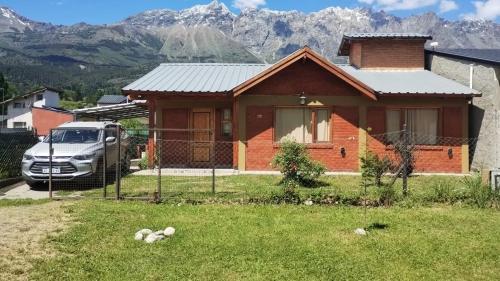 a truck parked in front of a house with mountains at Anlupa Casa in El Bolsón