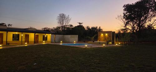 a backyard with a pool and a house with lights at San Cosme y Damian Lodge & Spa in San Cosme y Damián