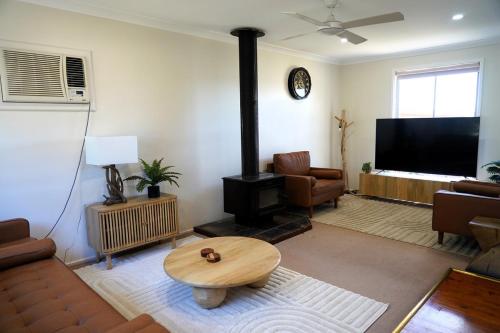 Denman Stay - Worker Friendly & Great Value في Denman: غرفة معيشة بها موقد وأريكة وطاولة