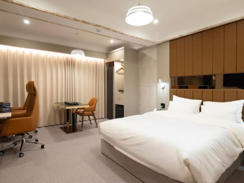 a bedroom with a large white bed and a desk at URBAN BROWN HOTEL Cheongju in Cheongju