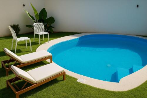 einen Pool mit 2 Stühlen, einem Tisch und 2 Stühlen in der Unterkunft Villas Carlota Cancún in Cancún