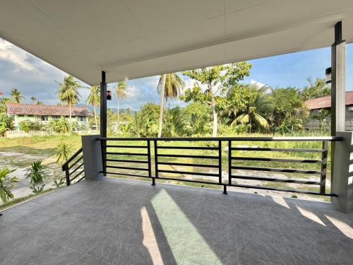 eine offene Veranda mit Zaun und Palmen in der Unterkunft Chon Nara Place in Thongsala