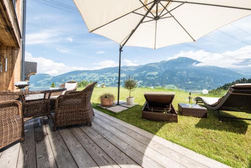 a wooden deck with chairs and an umbrella at Das Wiesegg in Fügenberg