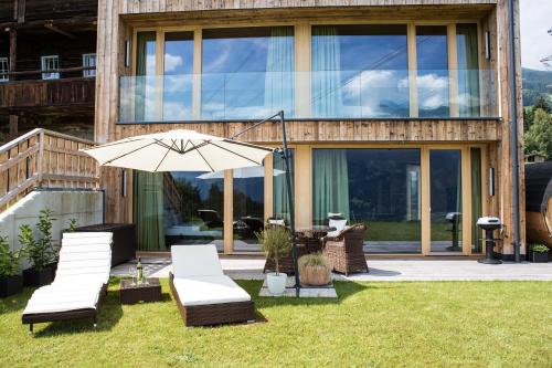 a patio with chairs and an umbrella in front of a house at Das Wiesegg in Fügenberg