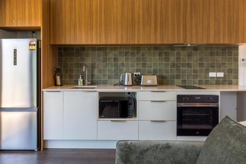 a kitchen with white appliances and a refrigerator at Hidden Valley Waiheke in Palm Beach