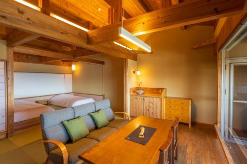 a bedroom with a bed and a table and a couch at Hamachidorinoyu Kaisyu in Shirahama