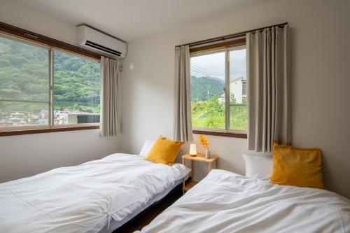 zwei Betten in einem Zimmer mit zwei Fenstern in der Unterkunft SAKURA HOUSE - Vacation STAY 07254v in Hakone