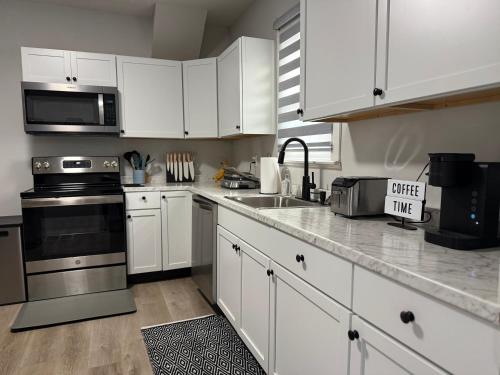 une cuisine avec des armoires blanches et des appareils en acier inoxydable dans l'établissement Rise & Shine, à Richmond