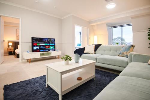 a living room with a couch and a tv at Luxury Perth Apartment near Optus in Perth