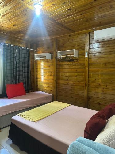 two beds in a room with wooden walls at Pousada Hostels Foryou in Ibiraçu