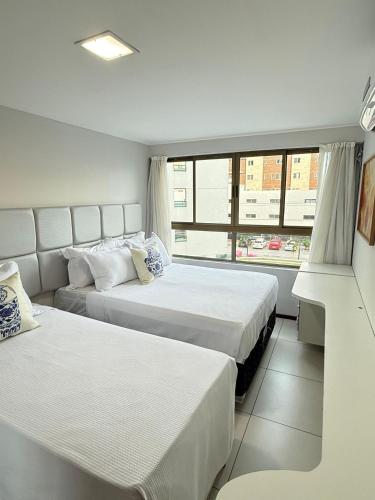 a hotel room with two beds and a window at Luxor Tambau 211 by Viva Hospedagens in Tambaú