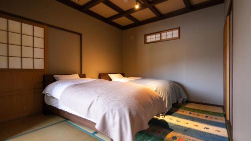 une chambre avec un lit blanc et une fenêtre dans l'établissement Yufuin Tsubaki, à Yufu