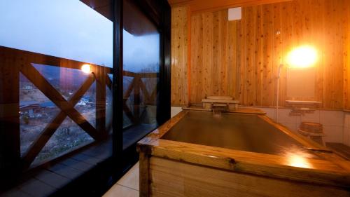 une grande baignoire en bois dans une pièce avec une fenêtre dans l'établissement Yufuin Tsubaki, à Yufu