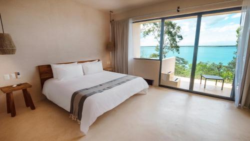 a bedroom with a bed and a large window at MBH Maya Bacalar Hotel Boutique in Bacalar