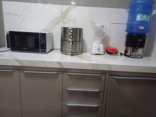 a kitchen counter with a microwave and a blender at Apartamento 2 quartos Ótima Localização in Uberlândia