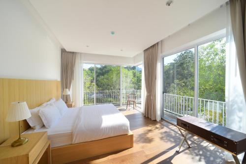 ein Schlafzimmer mit einem Bett und einem Balkon in der Unterkunft The Gallery Khao Yai Hotel and Residence - SHA Plus in Khao Yai