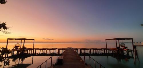a dock leading to the water at sunset at MBH Maya Bacalar Hotel Boutique in Bacalar