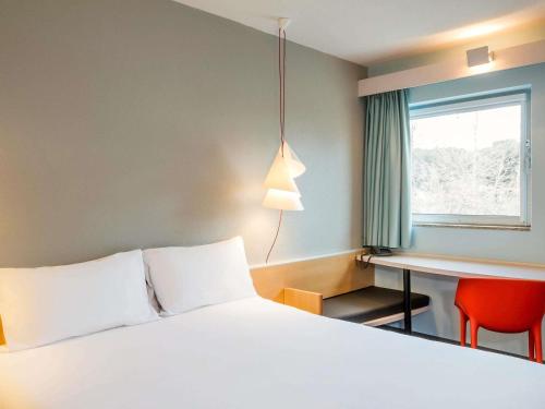 Una habitación de hotel con una cama, un escritorio y una ventana. en ibis Montélimar Nord, en Saulce-sur-Rhône