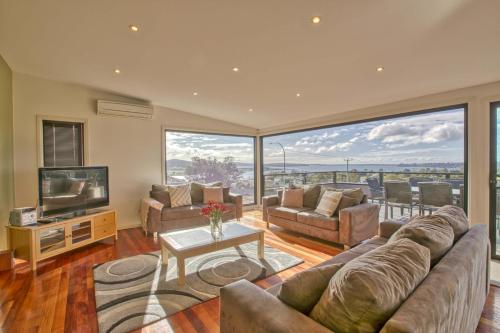 a large living room with a couch and a television at Georges Bay Luxury in St Helens