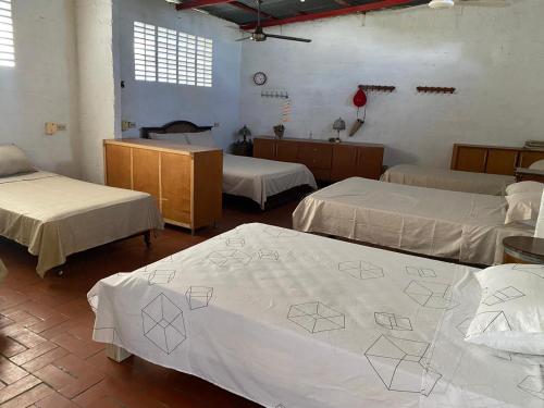 a room with three beds with white sheets at Finca La Camila in Coello