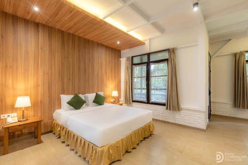 a bedroom with a large white bed and a window at Hotel Grand Panorama Lembang in Lembang